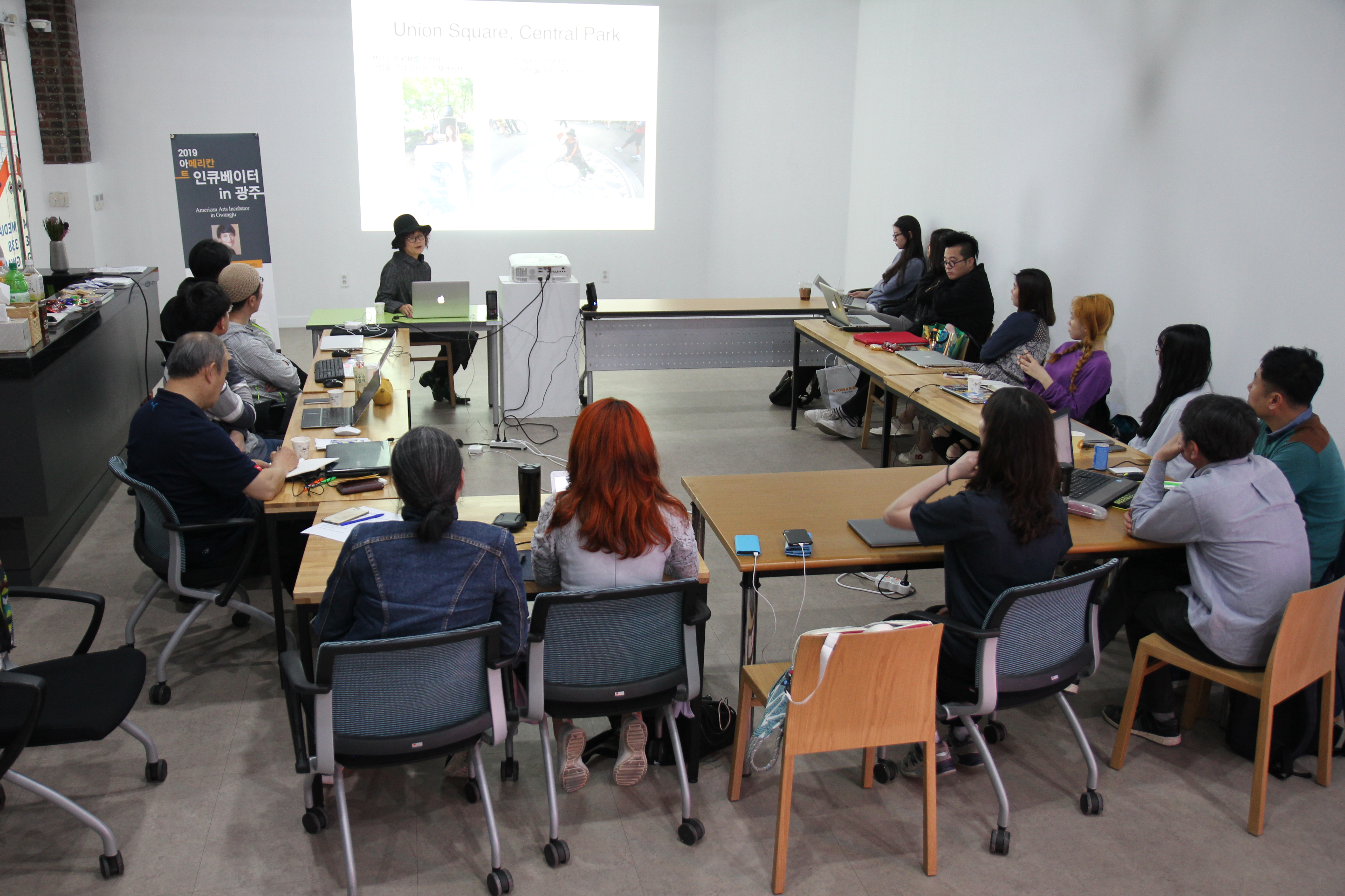 Group of people sit and listen to artist presentation