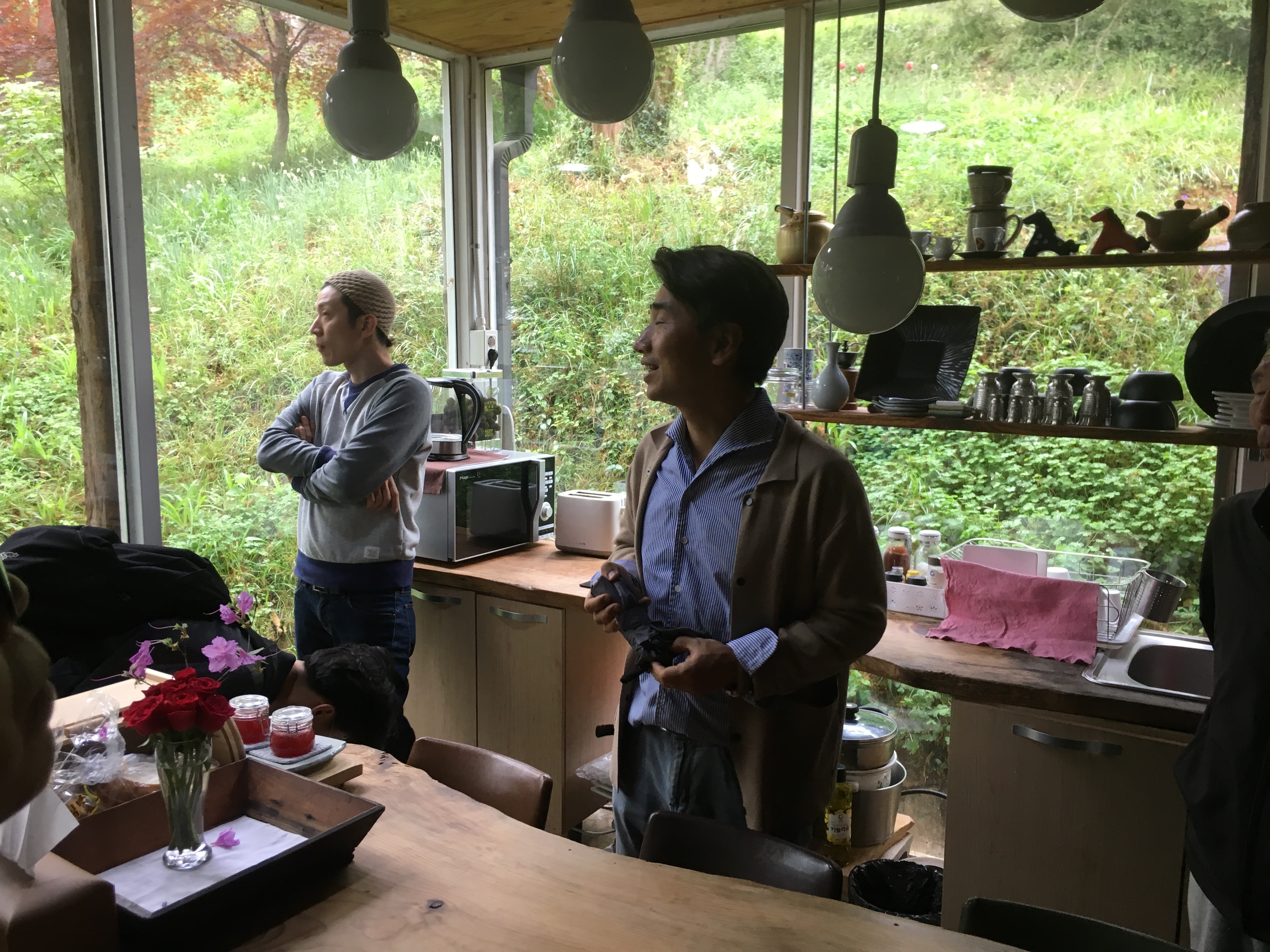 Man stands in kitchen surrounded by glass walls and greenery