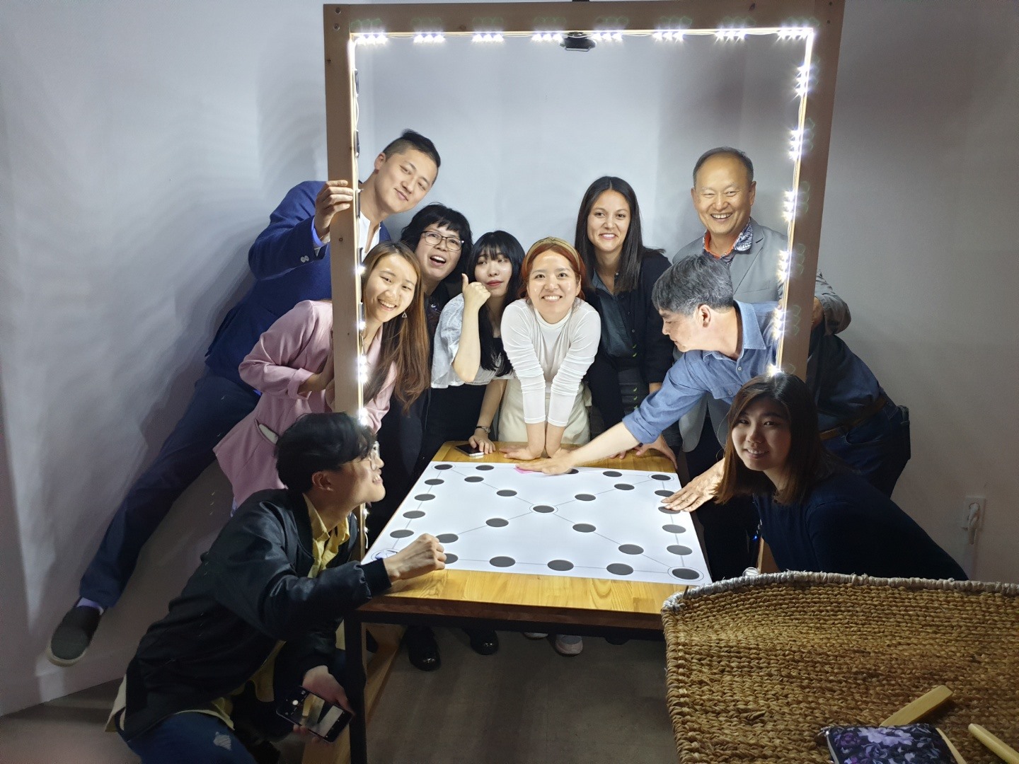 Group gathers around yutnori gameboard lit by LED frame